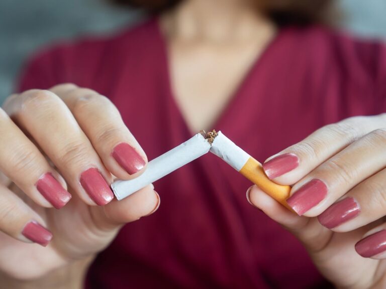 A woman breaking a cigarette in half.