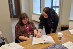 A learner is reviewing a workbook with WBFL trainer. They are engaged in conversation.